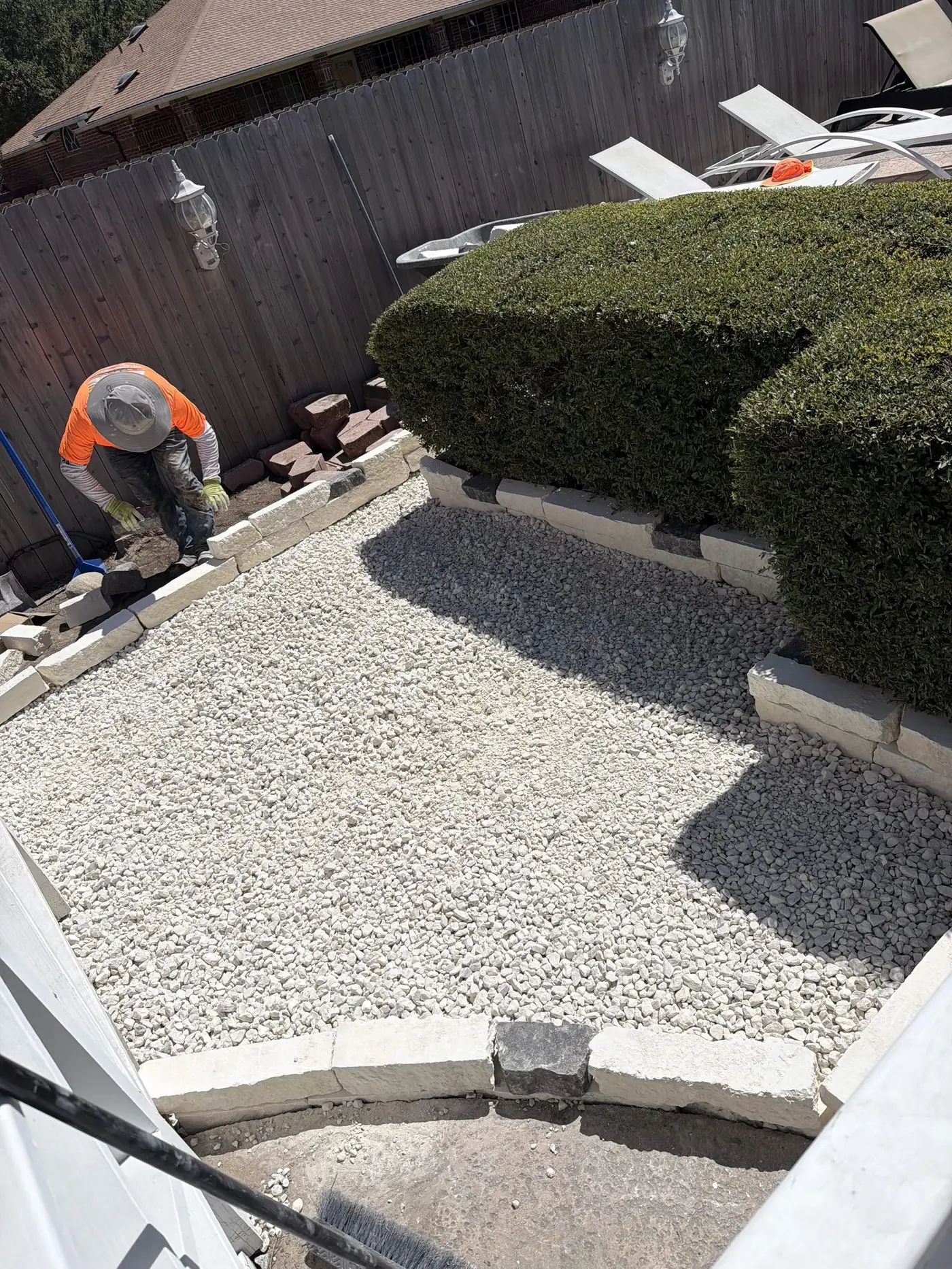 Decorative white rock bed with a new cut stone border being installed