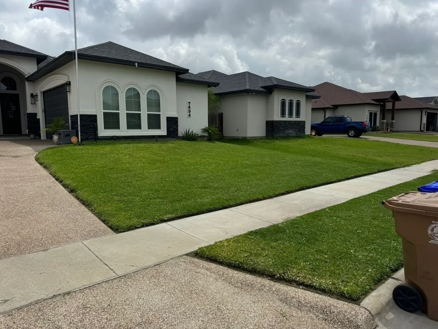 Freshly mowed and edged St. Augustine front lawn at a stucco home in Corpus Christi